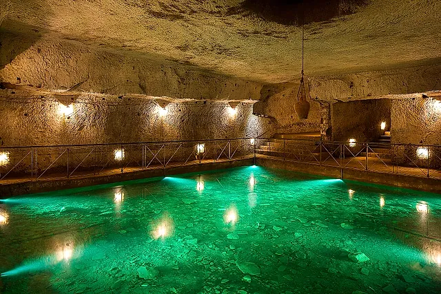 A Renaissance cistern with softly lit green water in the Galleria Borbonica, Naples