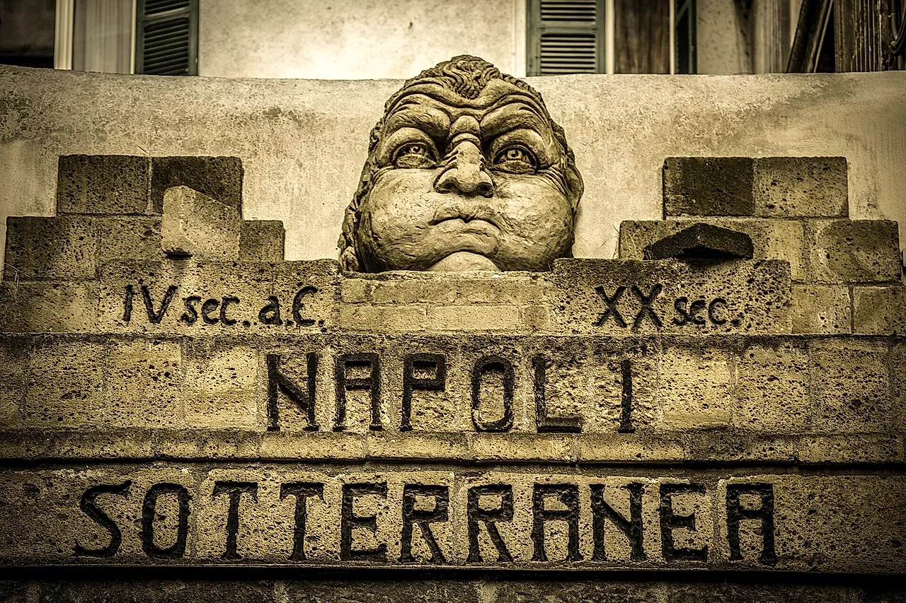 The tuff sculpture of Aeolus at the entrance of Napoli Sotterranea in Piazza San Gaetano